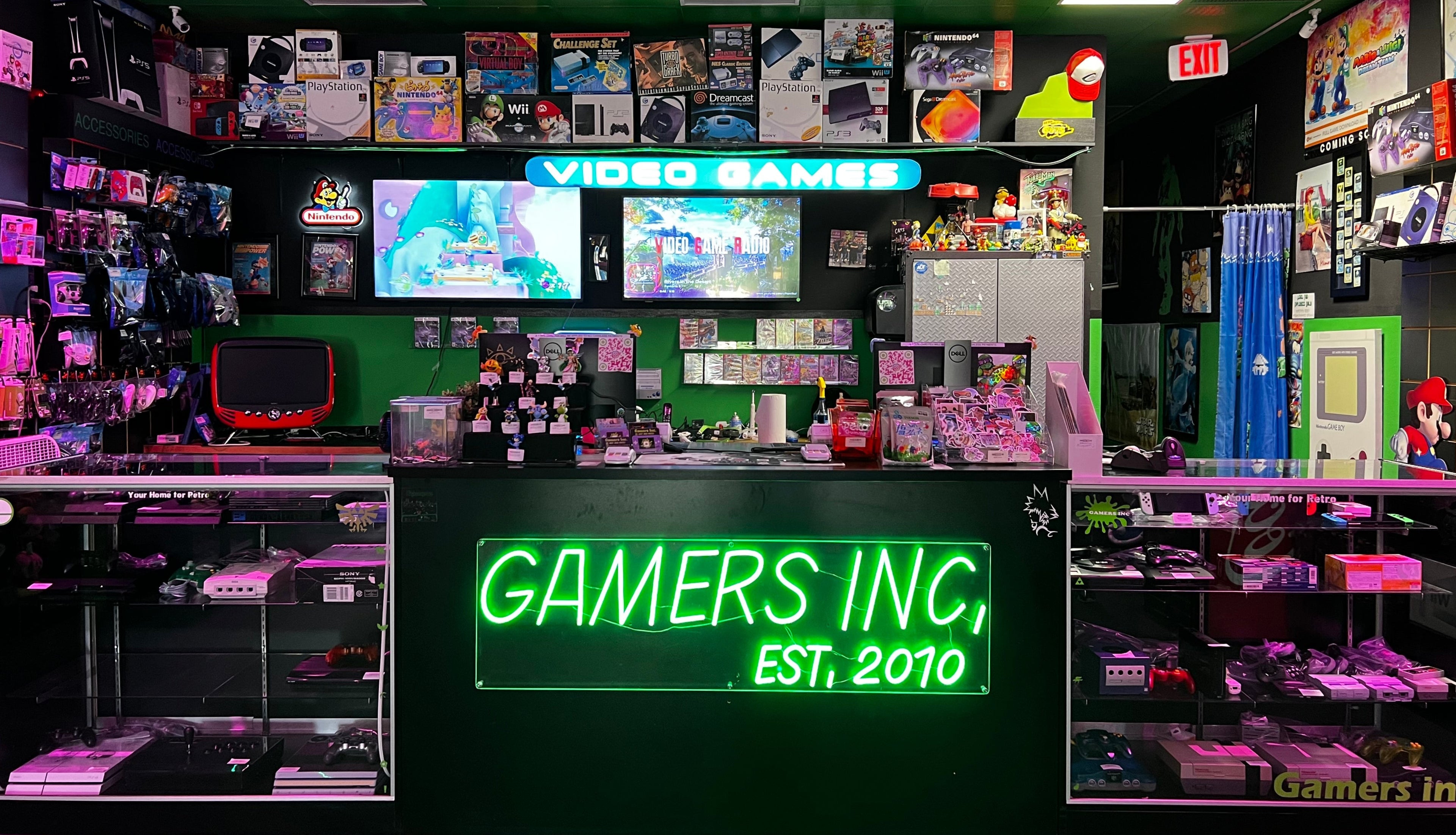 Video game arcade with 'Gamers Inc. Est. 2010' sign and various gaming equipment.