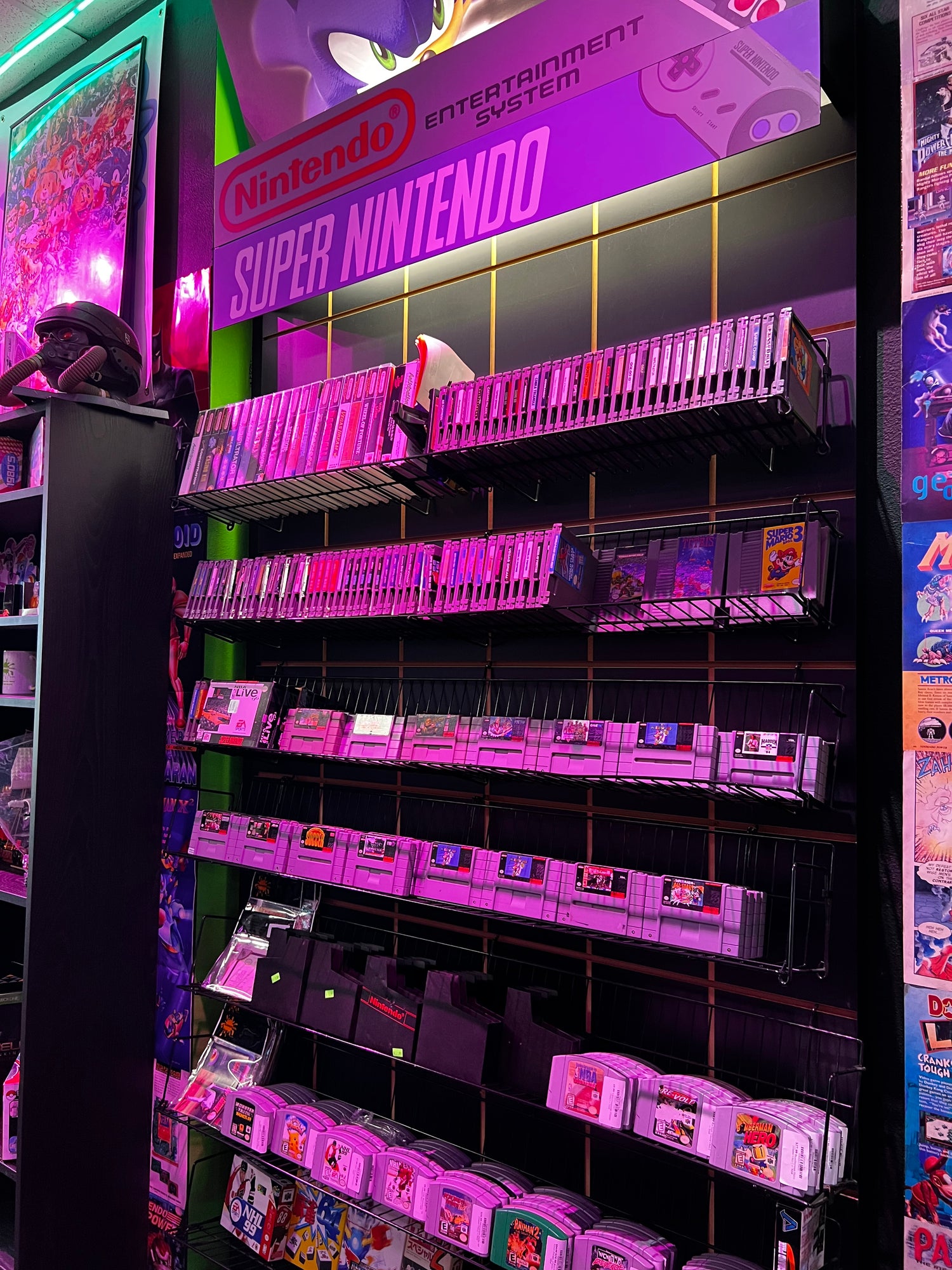 Collection of Super Nintendo games on a display shelf with a purple glow at Gamers Go Retro