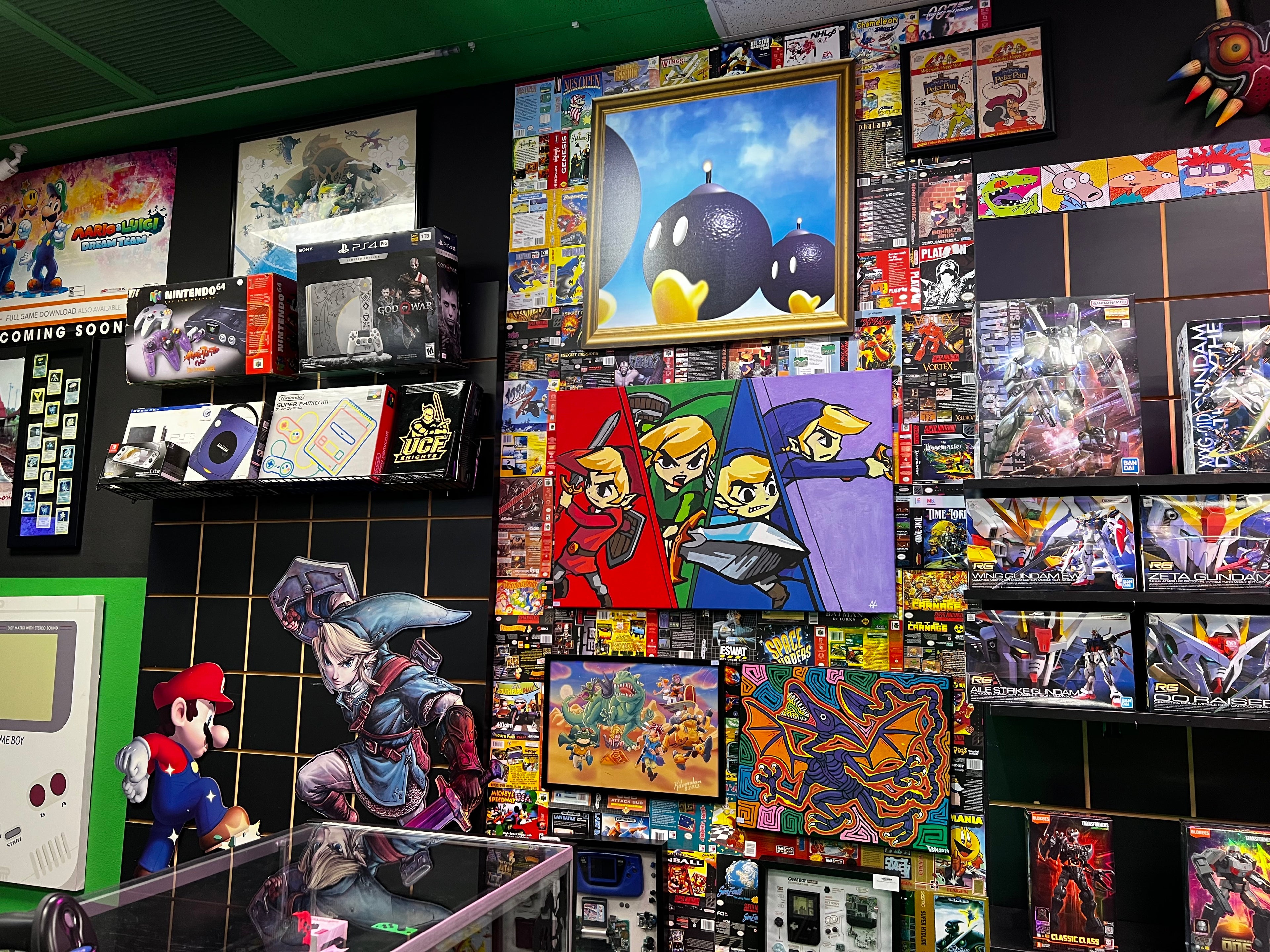 Display of video game merchandise with character figures and packaging on a tiled wall at Gamers Go Retro
