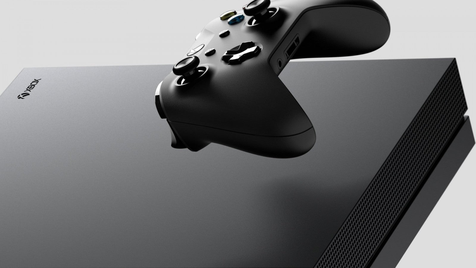Front view of a black Xbox One X gaming console with matching black wireless controller, disc drive, and textured finish