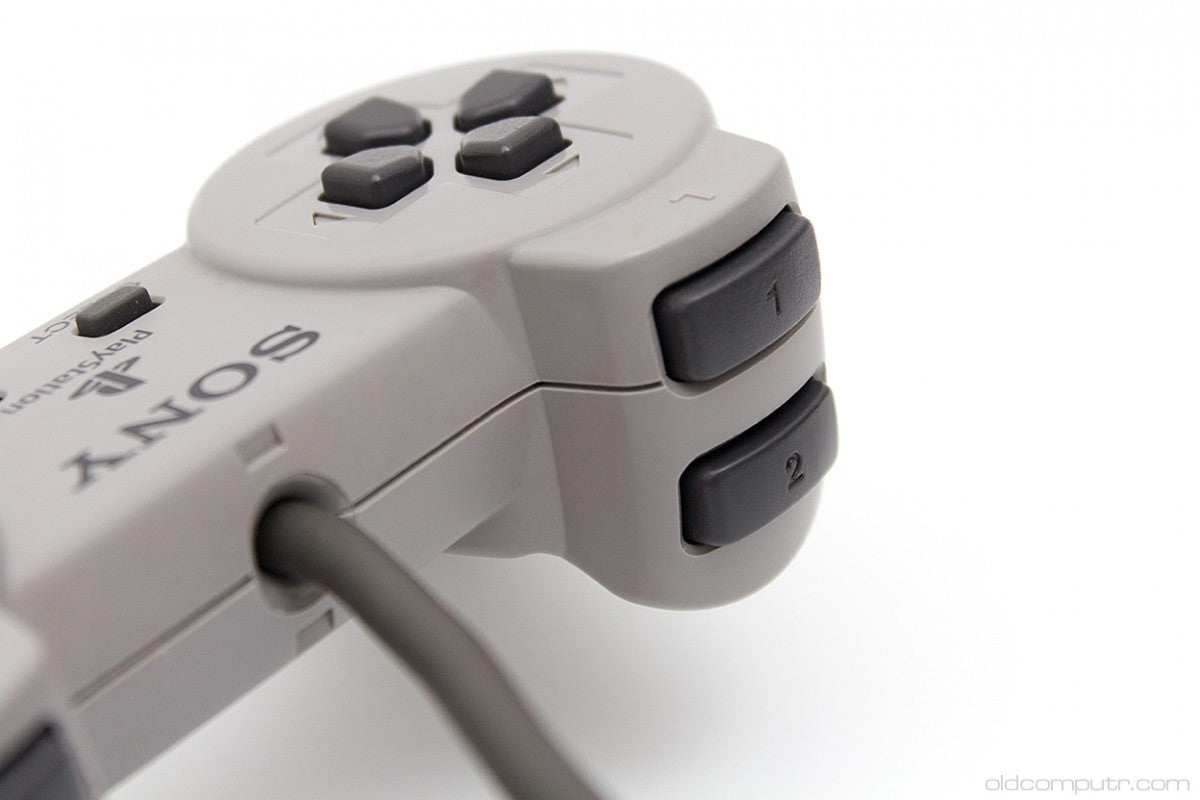 Original Sony PlayStation 1 controller with gray finish featuring directional pad, four action buttons, start and select buttons, and dual shoulder buttons