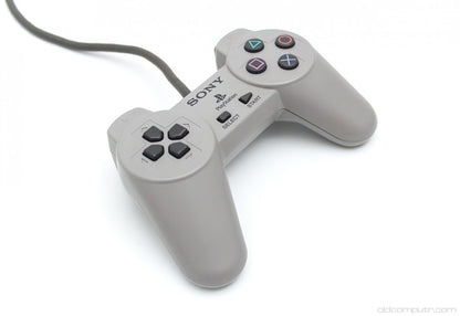 Original Sony PlayStation 1 controller with gray finish featuring directional pad, four action buttons, start and select buttons, and dual shoulder buttons