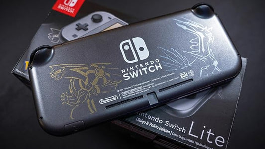 Nintendo Switch Lite Palkia and Dialga Edition console resting on top of its retail box, showing the dark gray casing with silver line art and the themed packaging beneath.