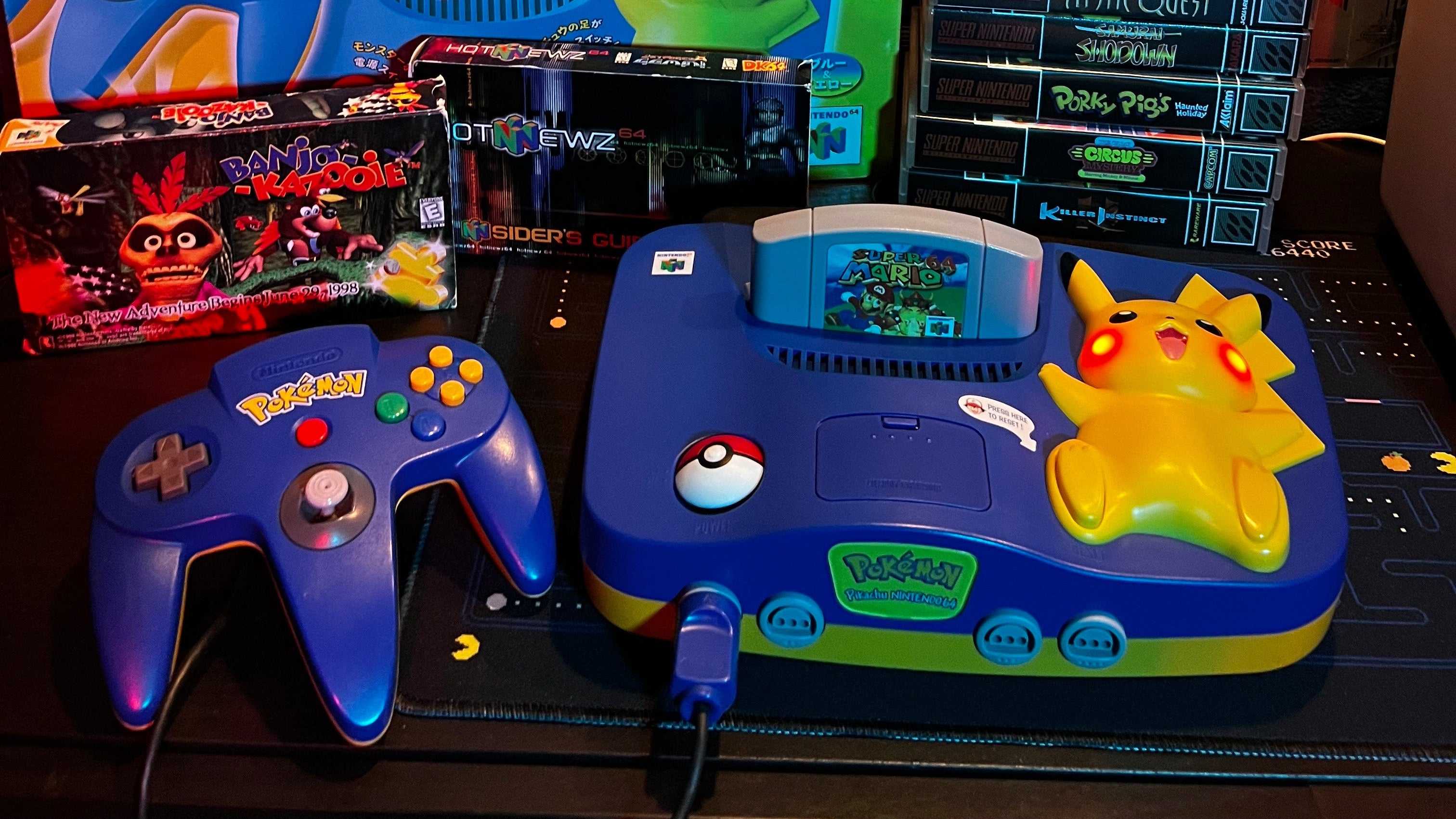 Collection of vintage gaming consoles and boxes on a dark surface with Pikachu N64 at  Gamers Inc Orlando Gamers Go Retro