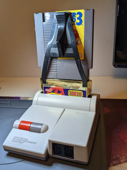 Game Genie for Nintendo Entertainment System (NES) at Gamers INC, featuring the legendary cheat-code breakthrough that unlocked a new dimension of gaming by allowing players to enter alphanumeric codes to bypass difficult levels, gain infinite lives, or discover hidden game features; this essential accessory includes the classic gold cartridge design and provides the ultimate power-up for your entire NES library, from Super Mario Bros. to The Legend of Zelda plugged in NES