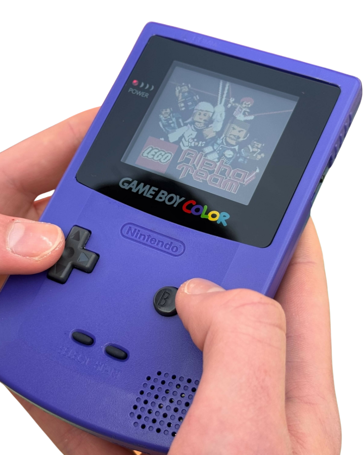 Hands holding a grape purple Nintendo Game Boy Color while pressing buttons and playing a game.