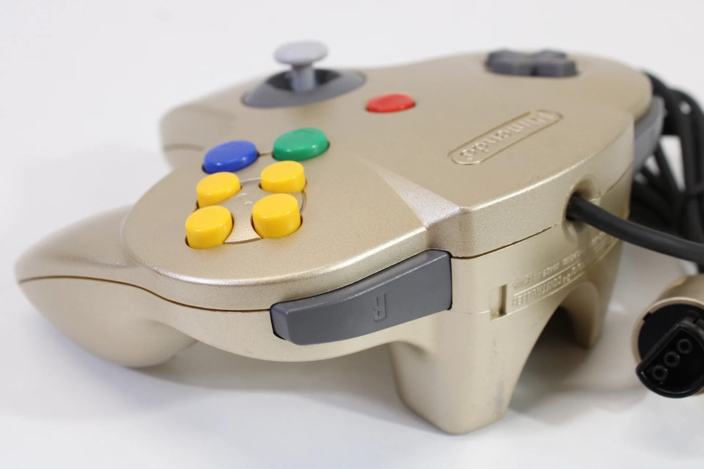 Top corner view of the gold Nintendo 64 controller, highlighting the joystick, shoulder buttons, and part of the D-pad for detailed perspective of the controller design