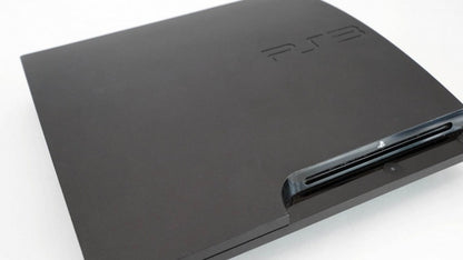 Angled front view of a Sony PS3 Slim console showing the disc slot, power and eject buttons, logo, and top surface from a slight side perspective.