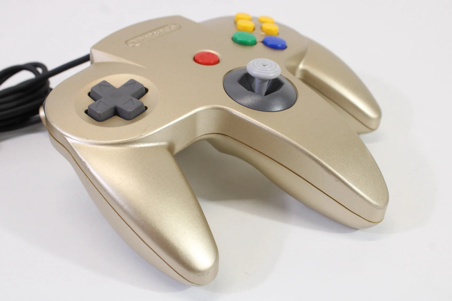 Left side view of the gold Nintendo 64 controller, showing D-pad, ergonomic grip, and side contours for comfortable gameplay