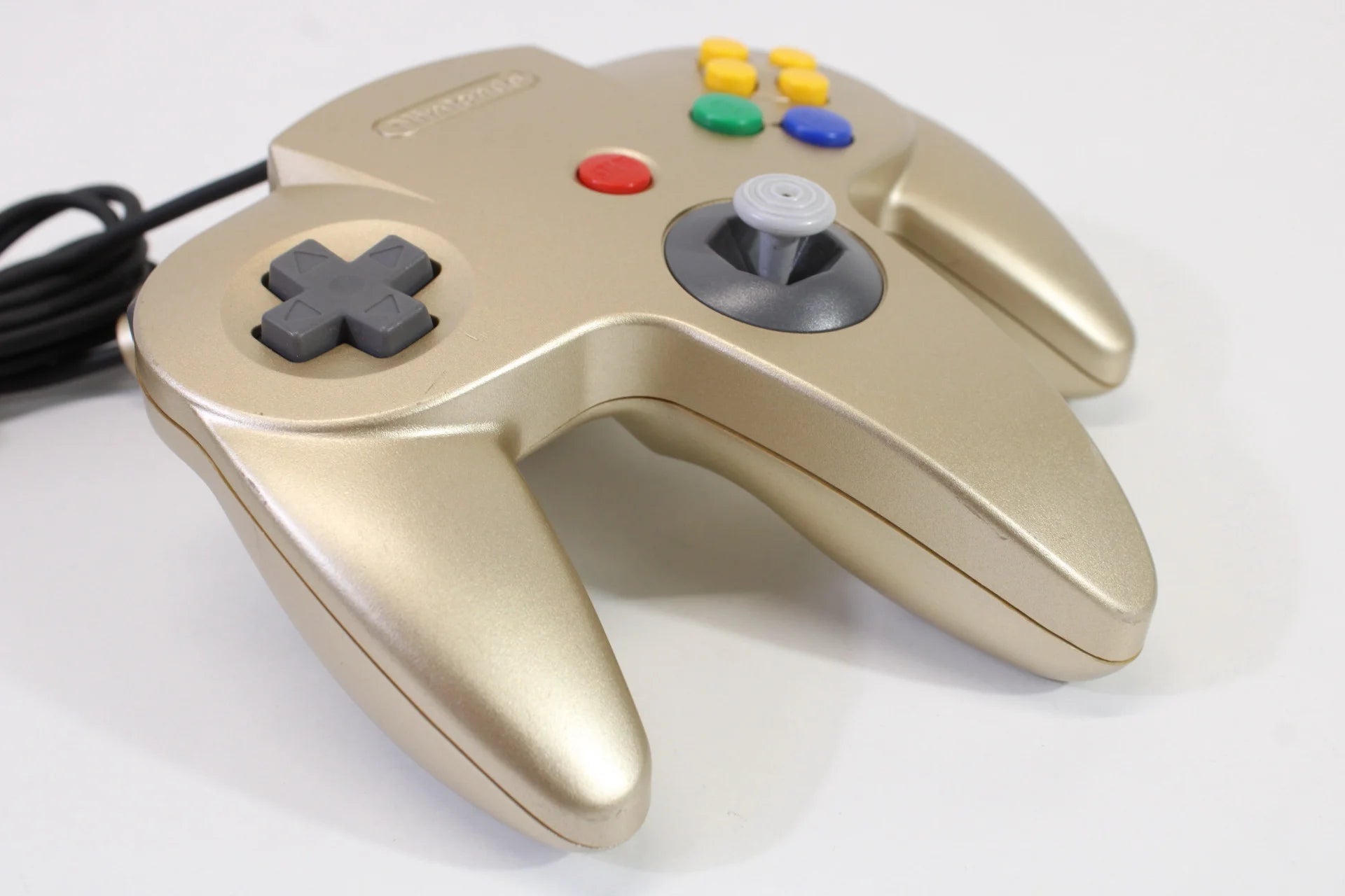 Left side view of the gold Nintendo 64 controller, showing D-pad, ergonomic grip, and side contours for comfortable gameplay