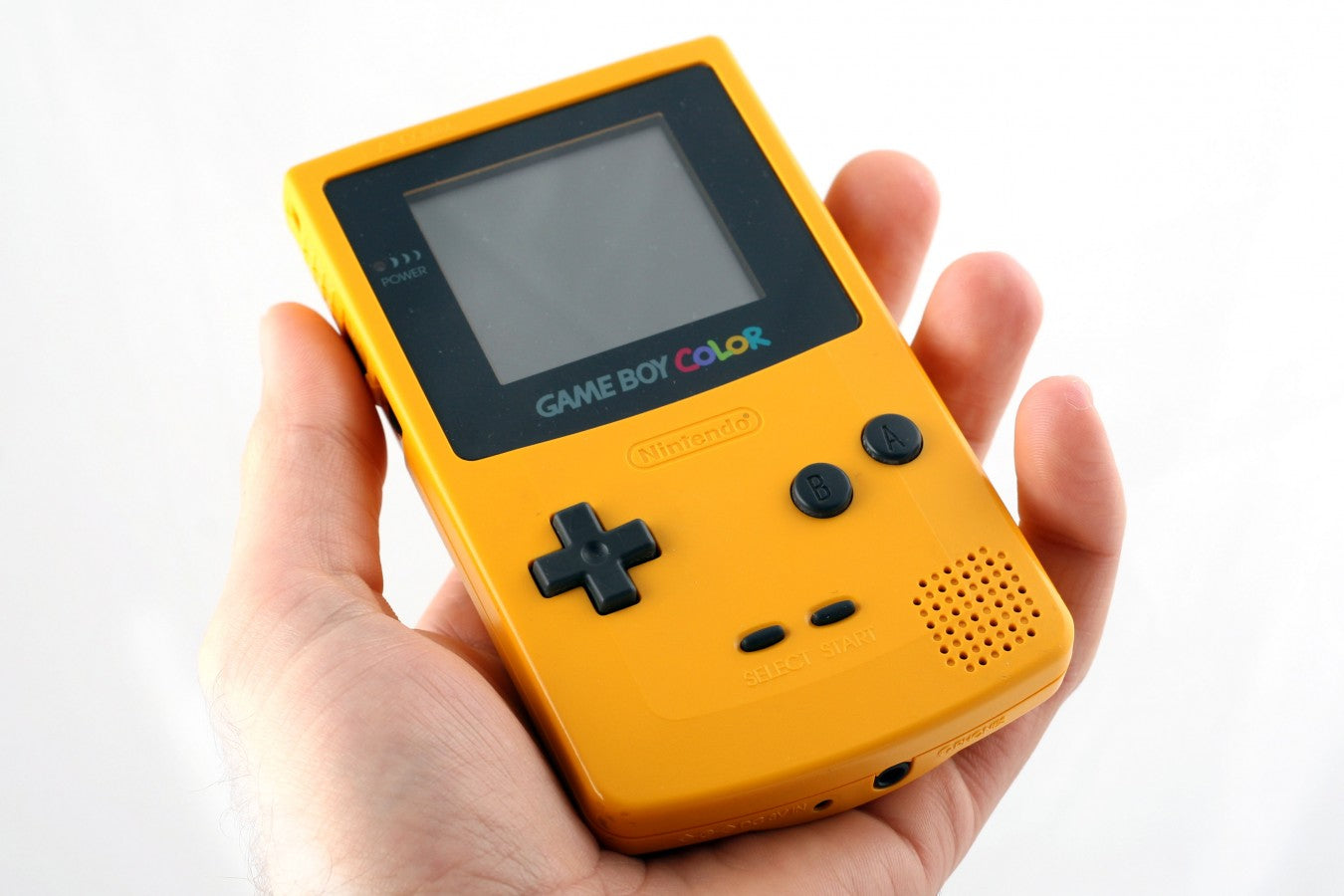 Hand holding a yellow Nintendo Game Boy Color handheld console with screen and buttons visible.